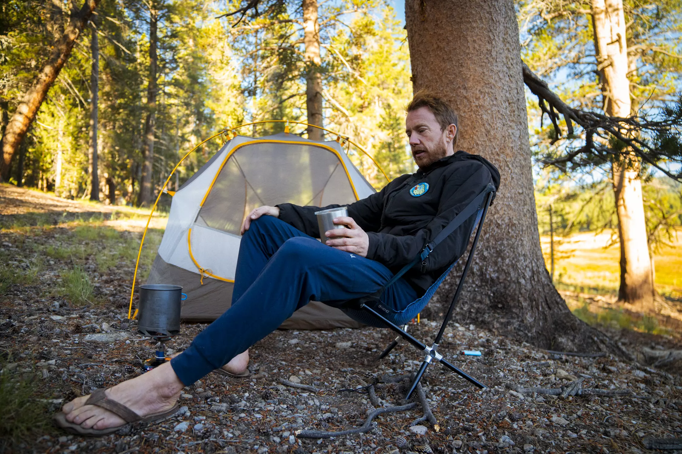 A man lounges in a backpacking chair at camp