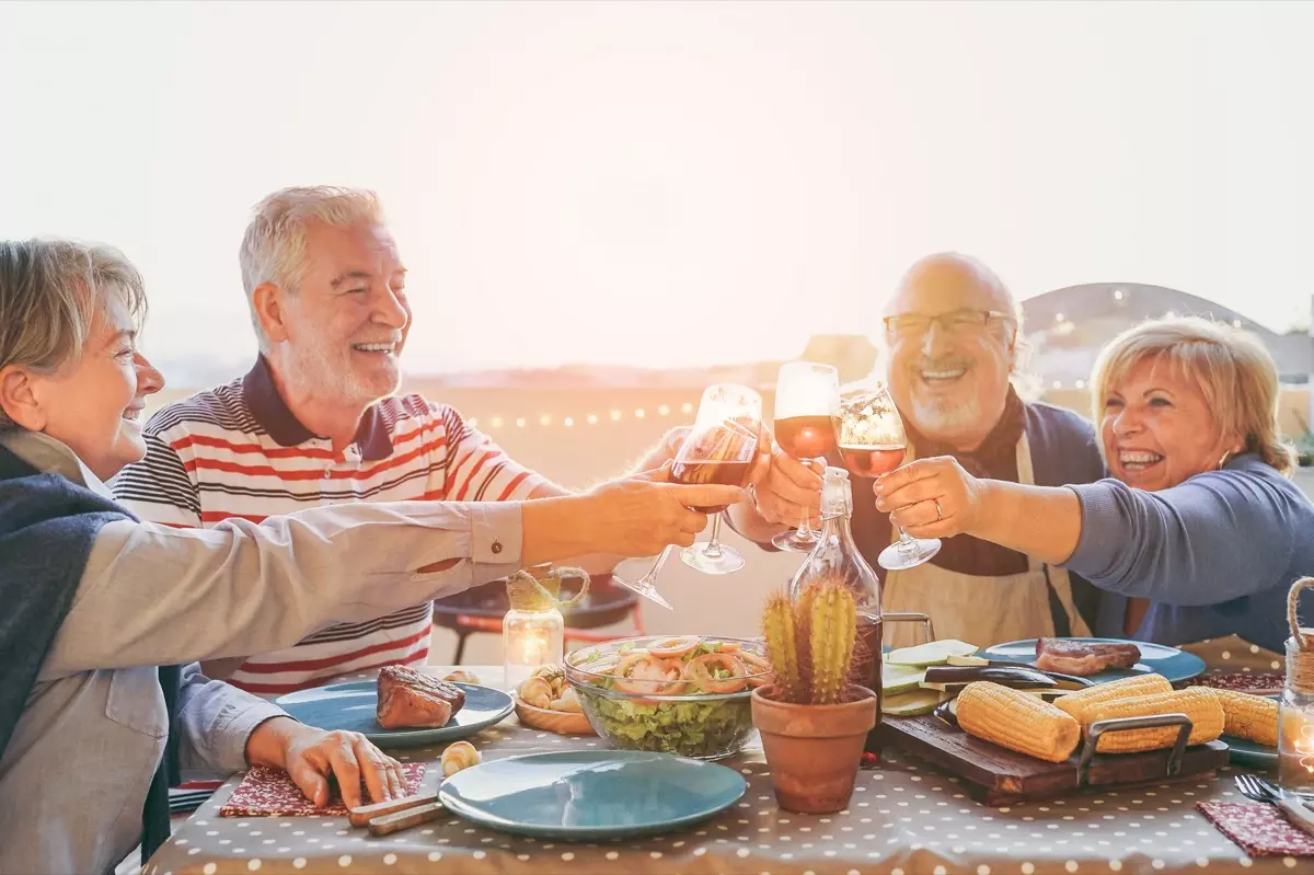 Older friends doing a cheers and drinking together