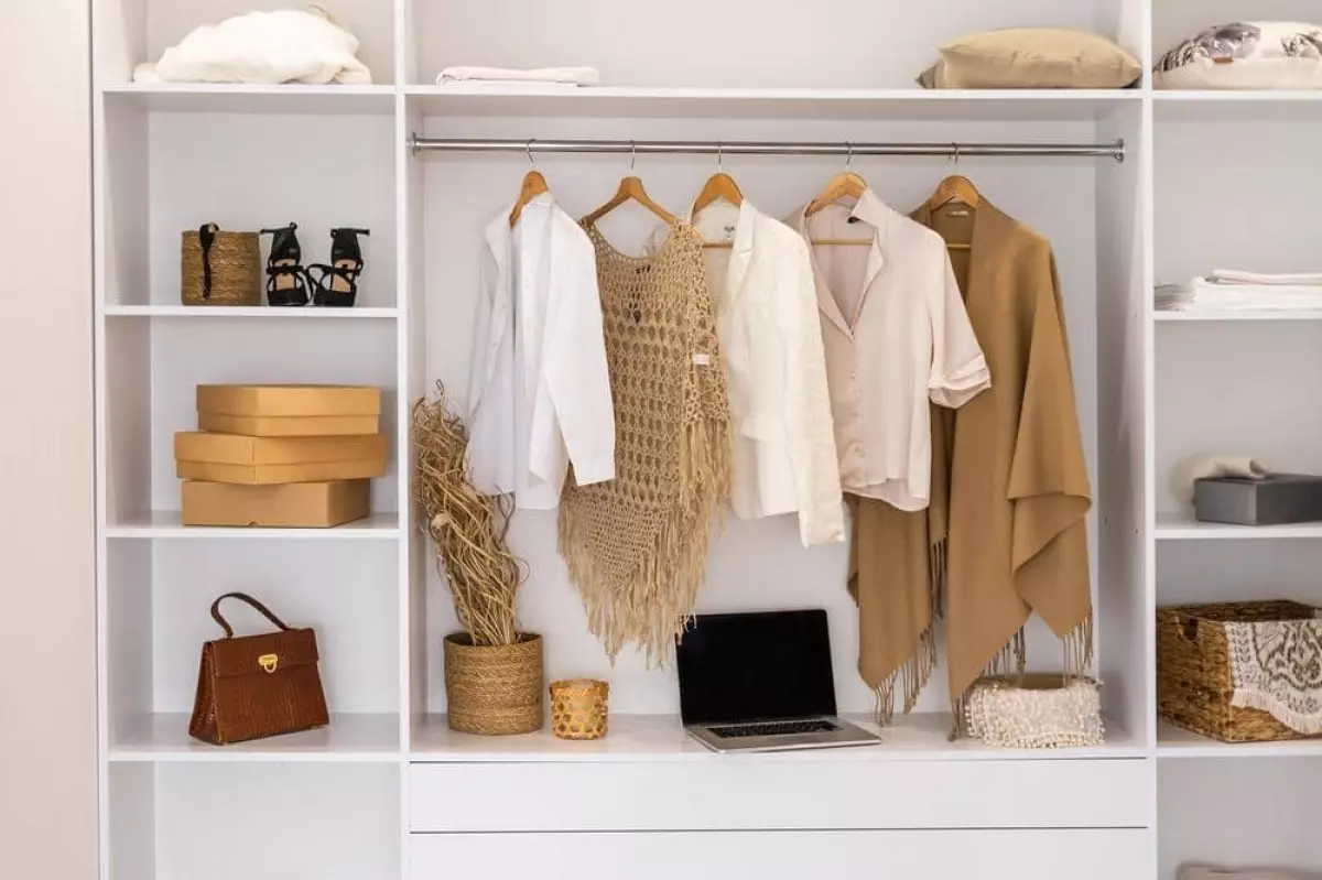 White closet that has clothes hanging on its hangers and shelves