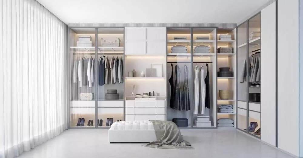 Modern closet with glass doors and ottoman in front of it