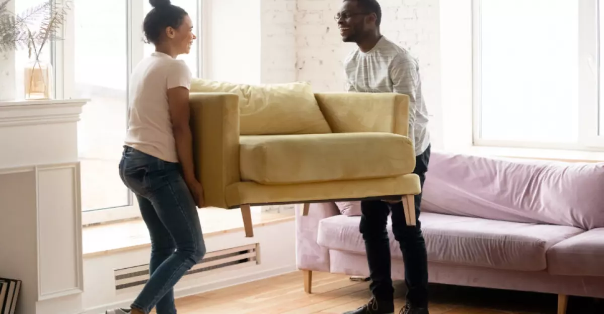 Couple moving into a new home and carrying a couch.