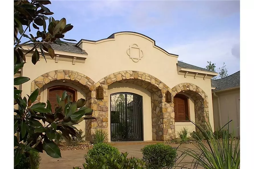 Spanish style home with a beige stucco, scalloped parapet, and red-tile hip roof