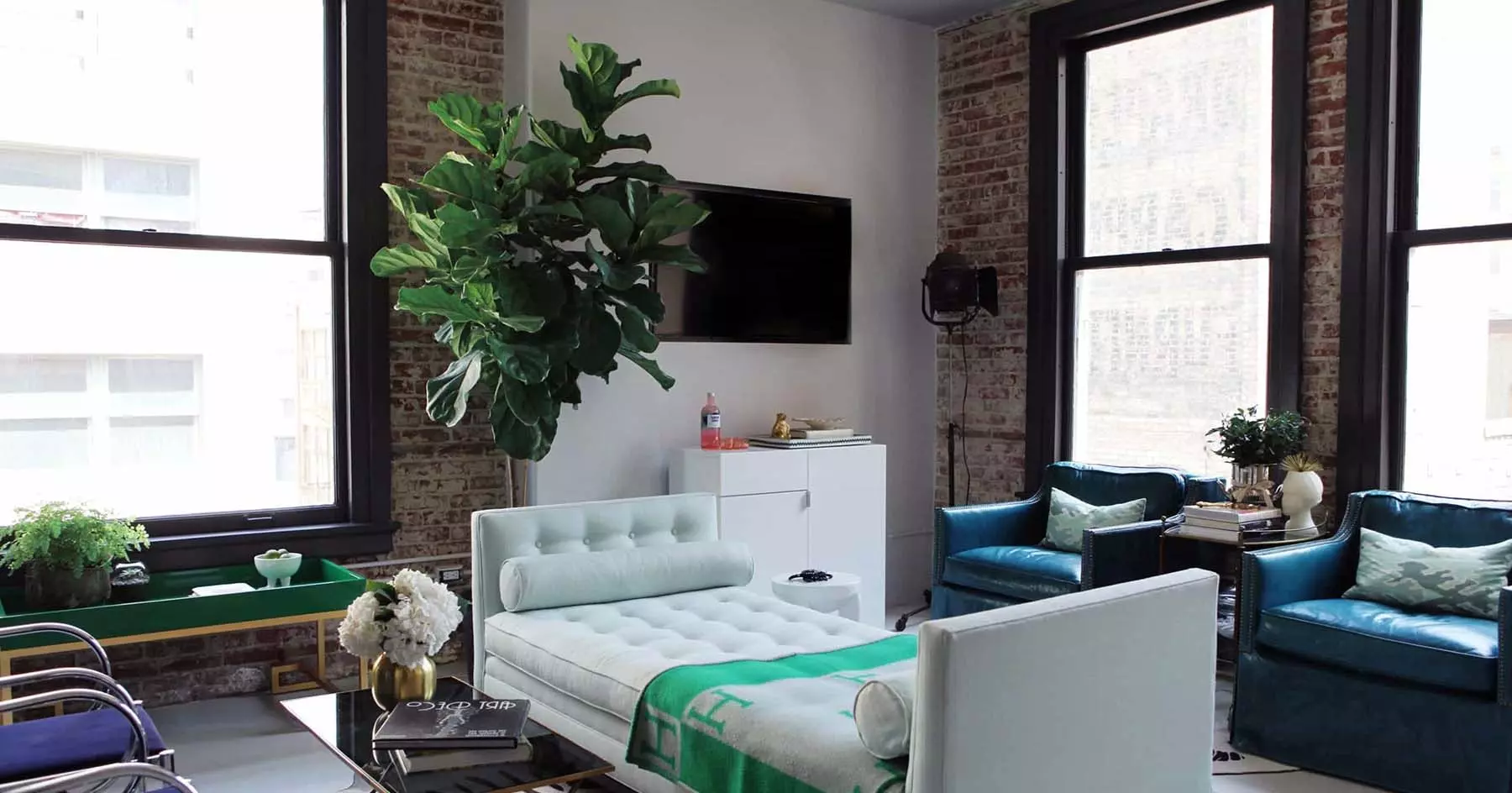 City apartment with red brick walls that are slightly white washed. Black frame windows with drywall and concrete floors give the room a modern feel.