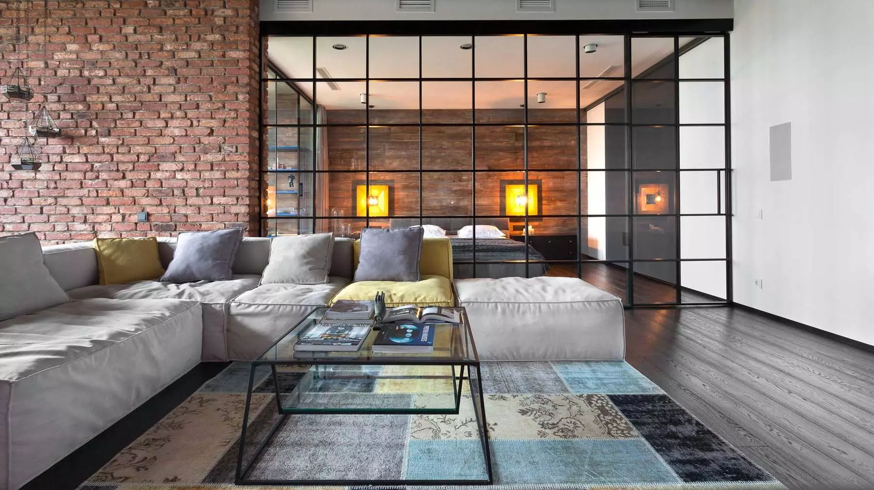 Red brick wall in a modern home featuring an all-glass bedroom wall. Dark hardwood floors with white walls.