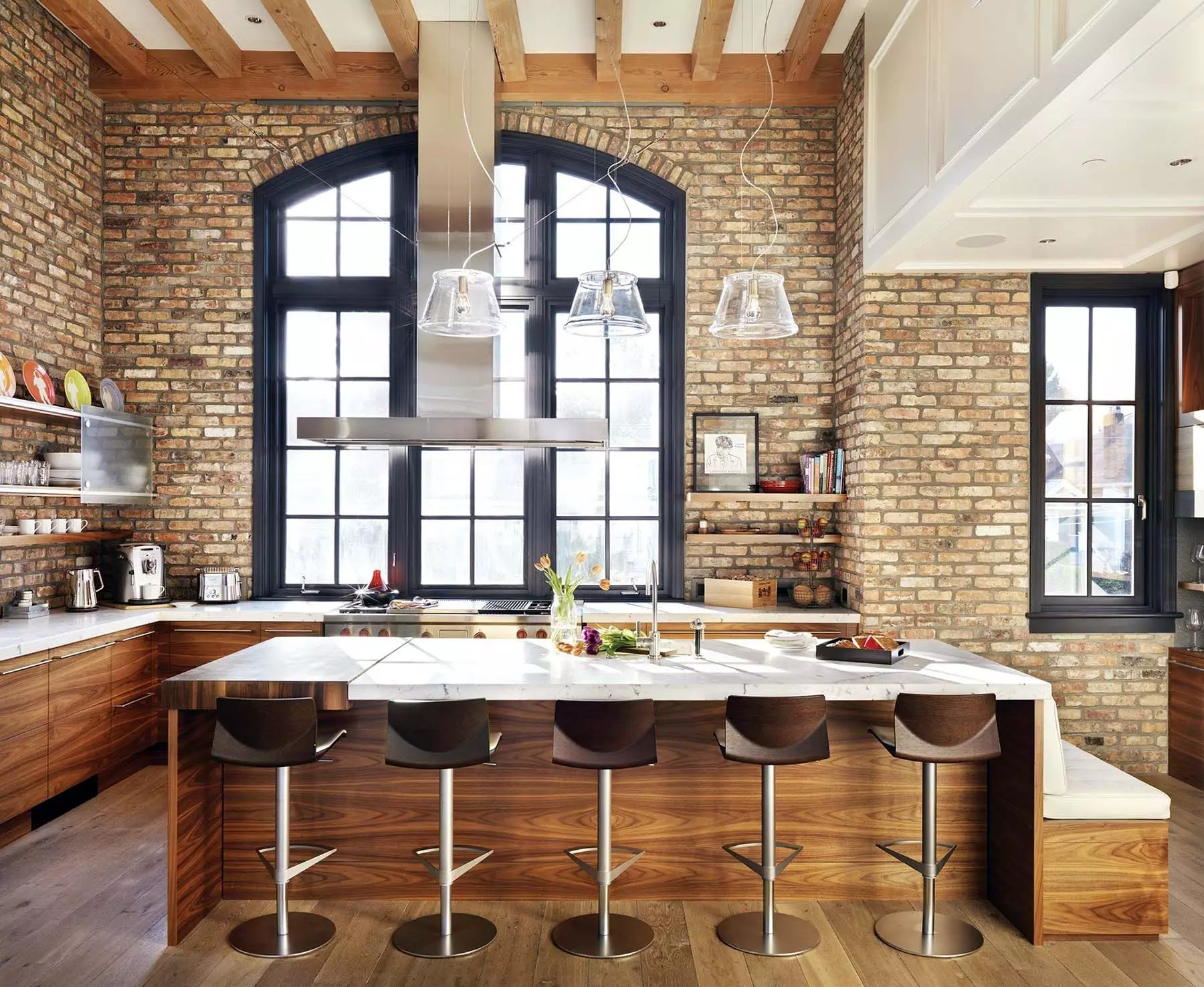 Beautiful contemporary kitchen design with cathedral ceilings, exposed wood beams, real wood flat-faced cabinets, and red brick walls.