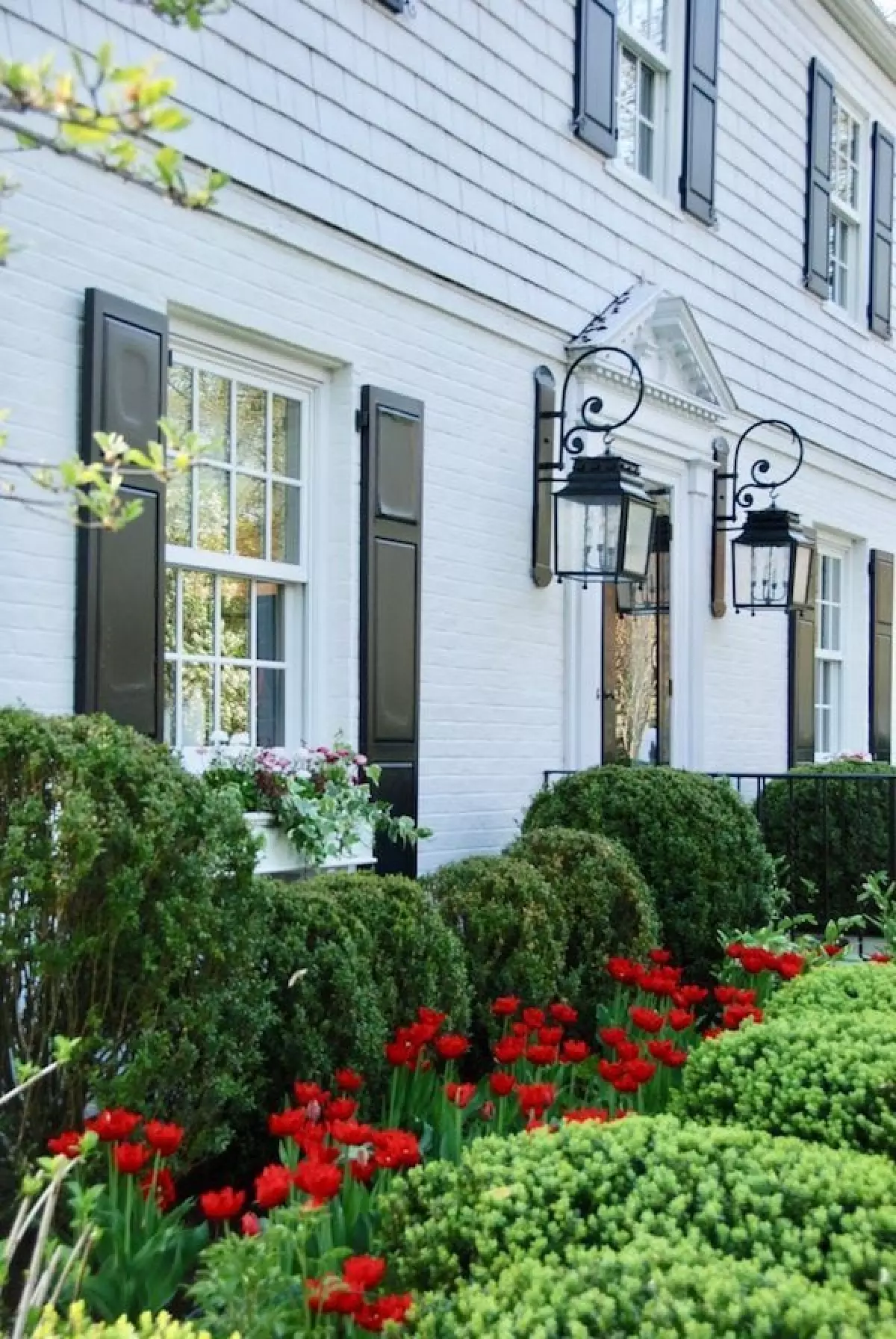 Black lanterns flanking front door of white brick home