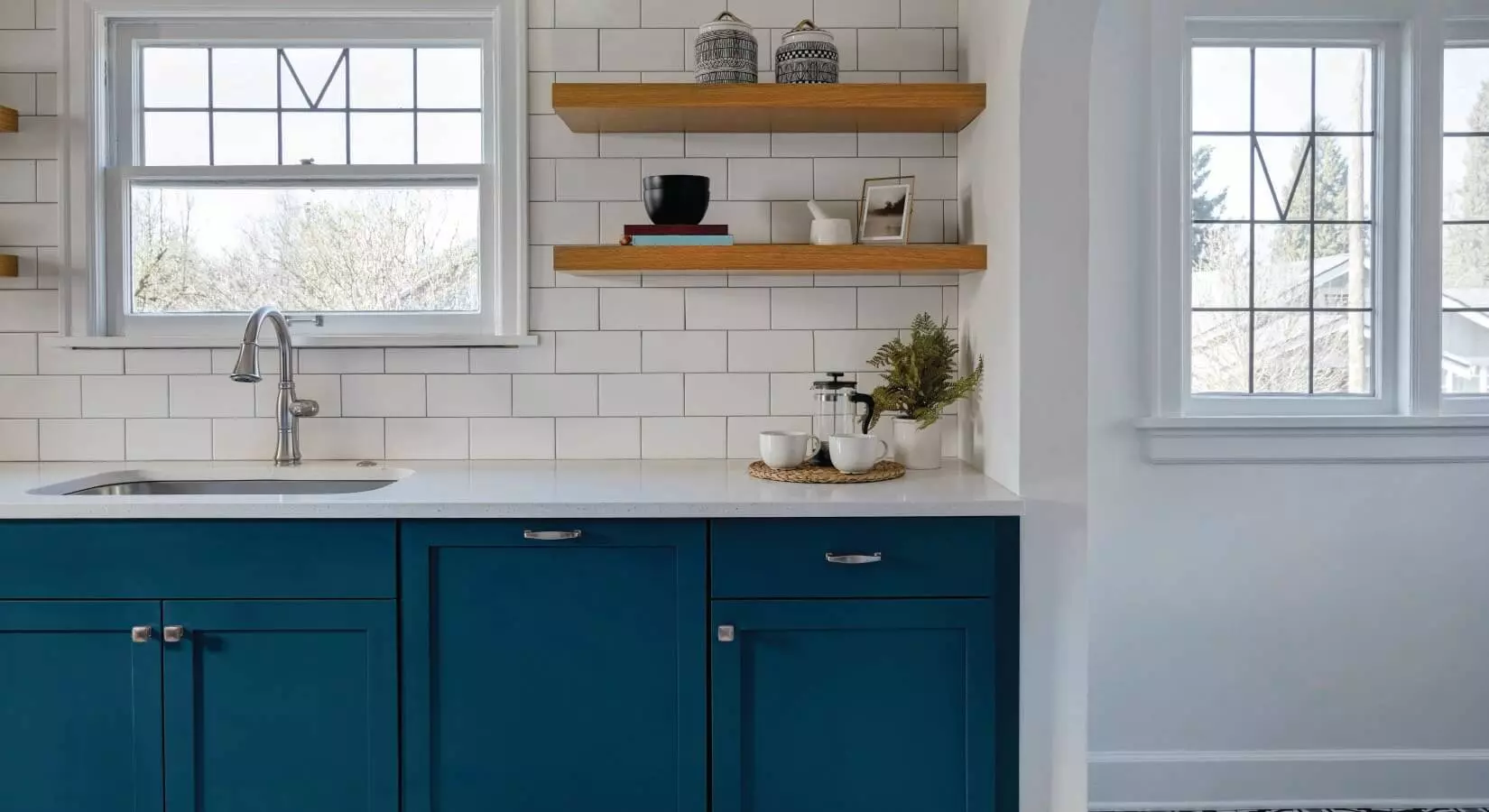 Small kitchen with navy blue cabinets, butcher block countertops, and yellow and blue Moroccan patterned backsplash.