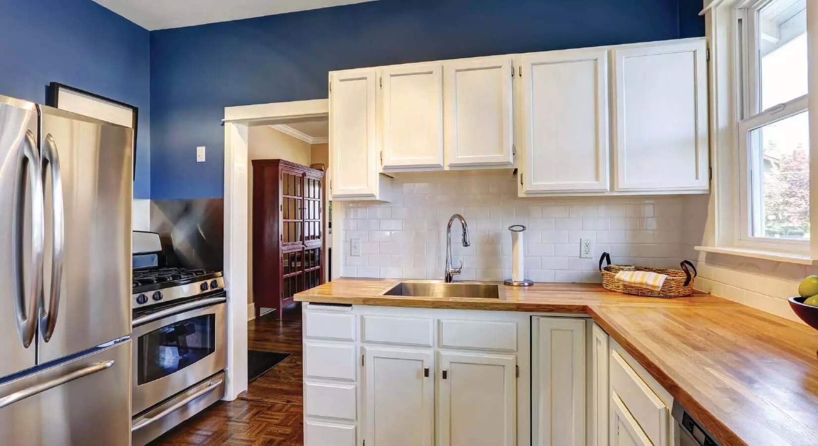 Kitchen with dark blue cabinets, gray tile backsplash, and gray barstools.