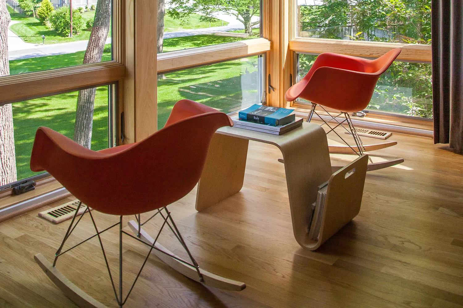 A wooden table with books between two chairs.