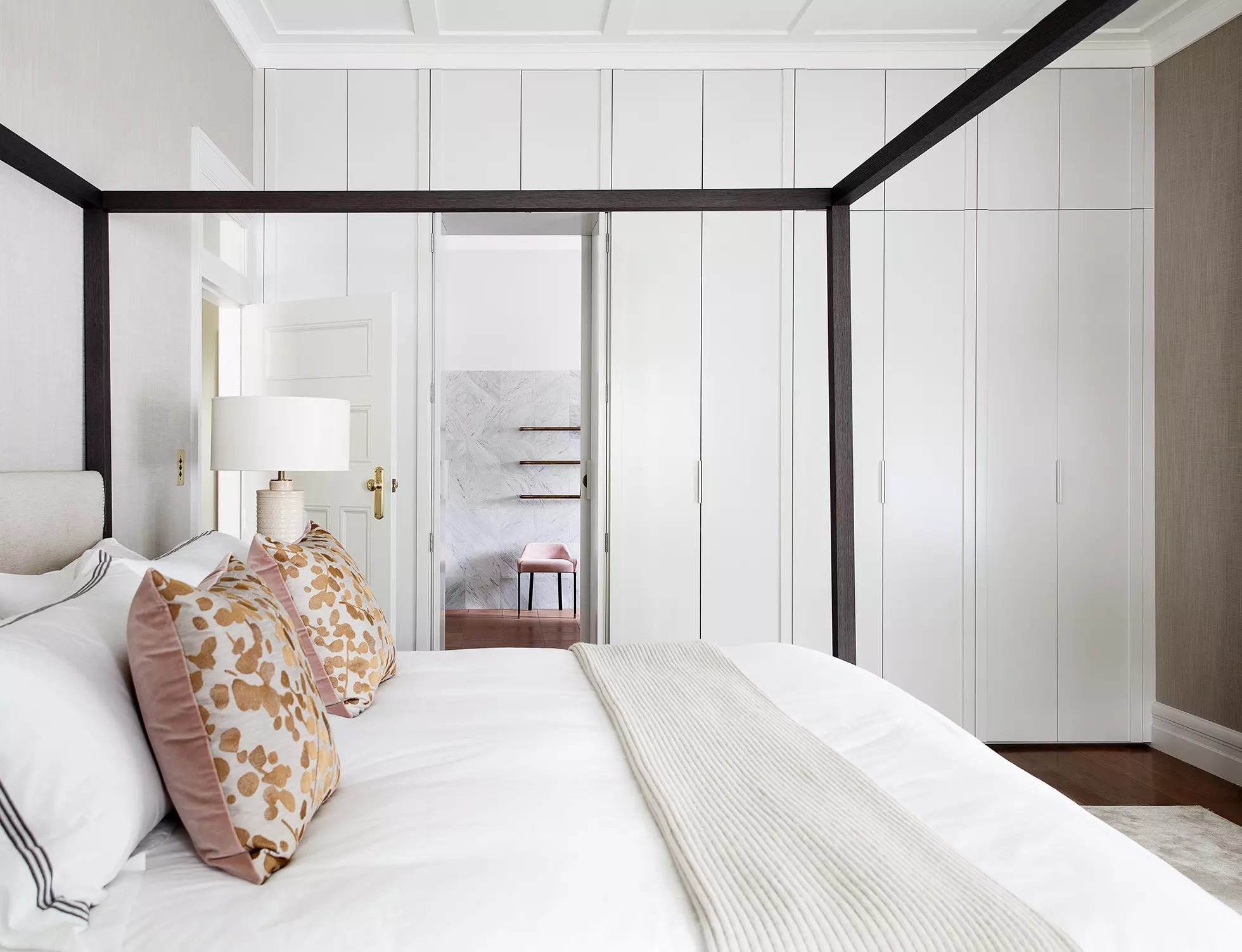 White bedroom with white canopy bed and pink pillows