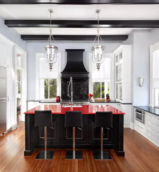 a set of red custom cabinets paired with black island in an eclectic kitchen