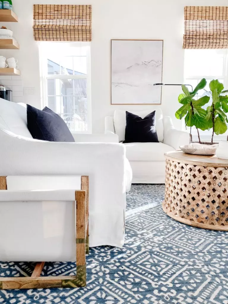 Our living room, with 2 white swivel chairs, a striped jute rug, woven ottomans and neutral furniture and decor - jane at home