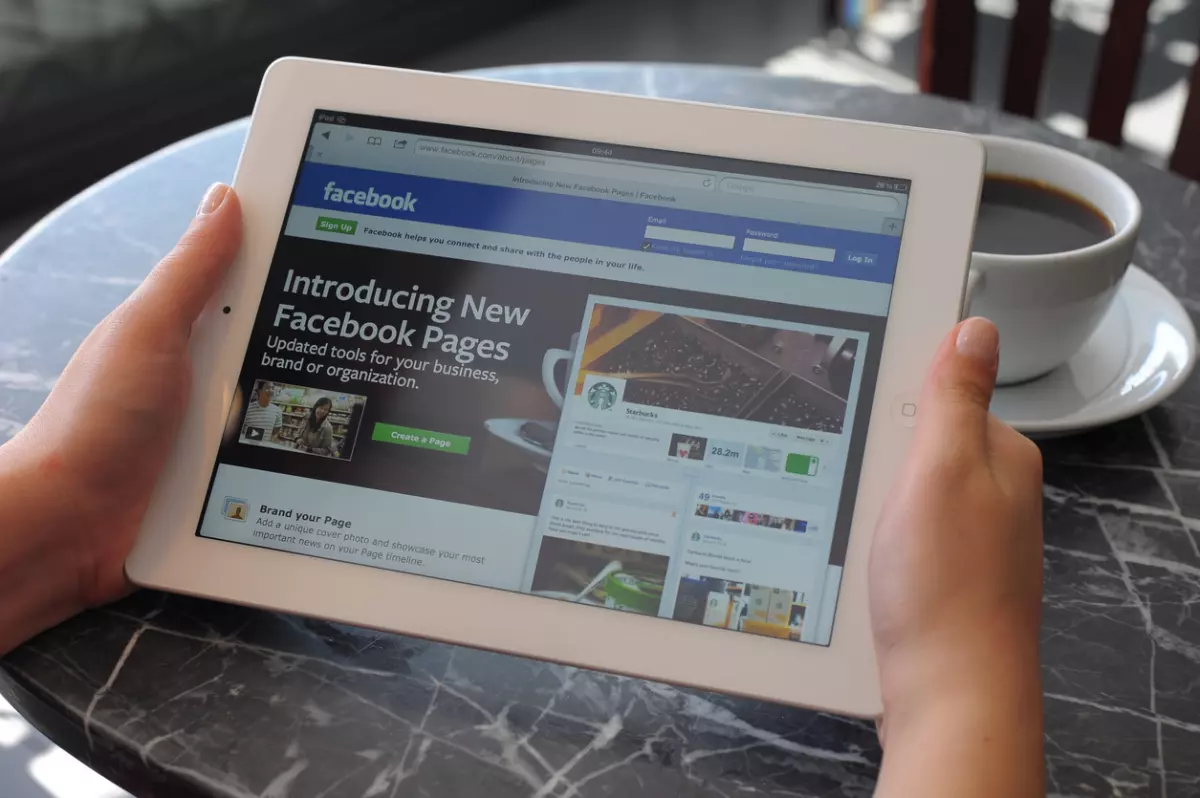 person holding ipad with facebook page open