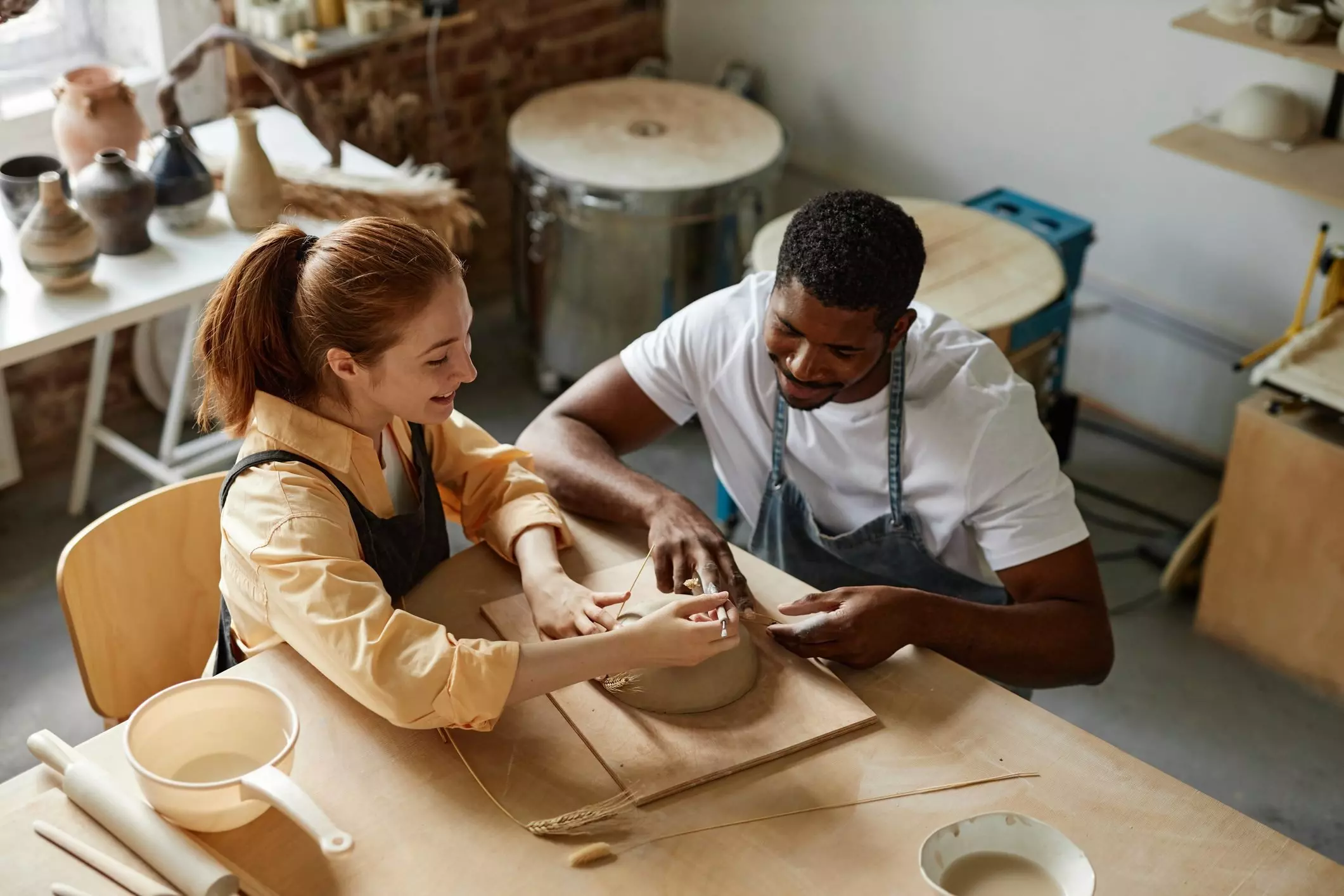 Couple decorating handmade ceramics in pottery studio