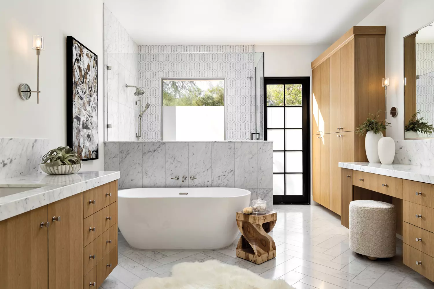 Spa-like bathroom with white oak cabinetry, a freestanding tub and marble floors