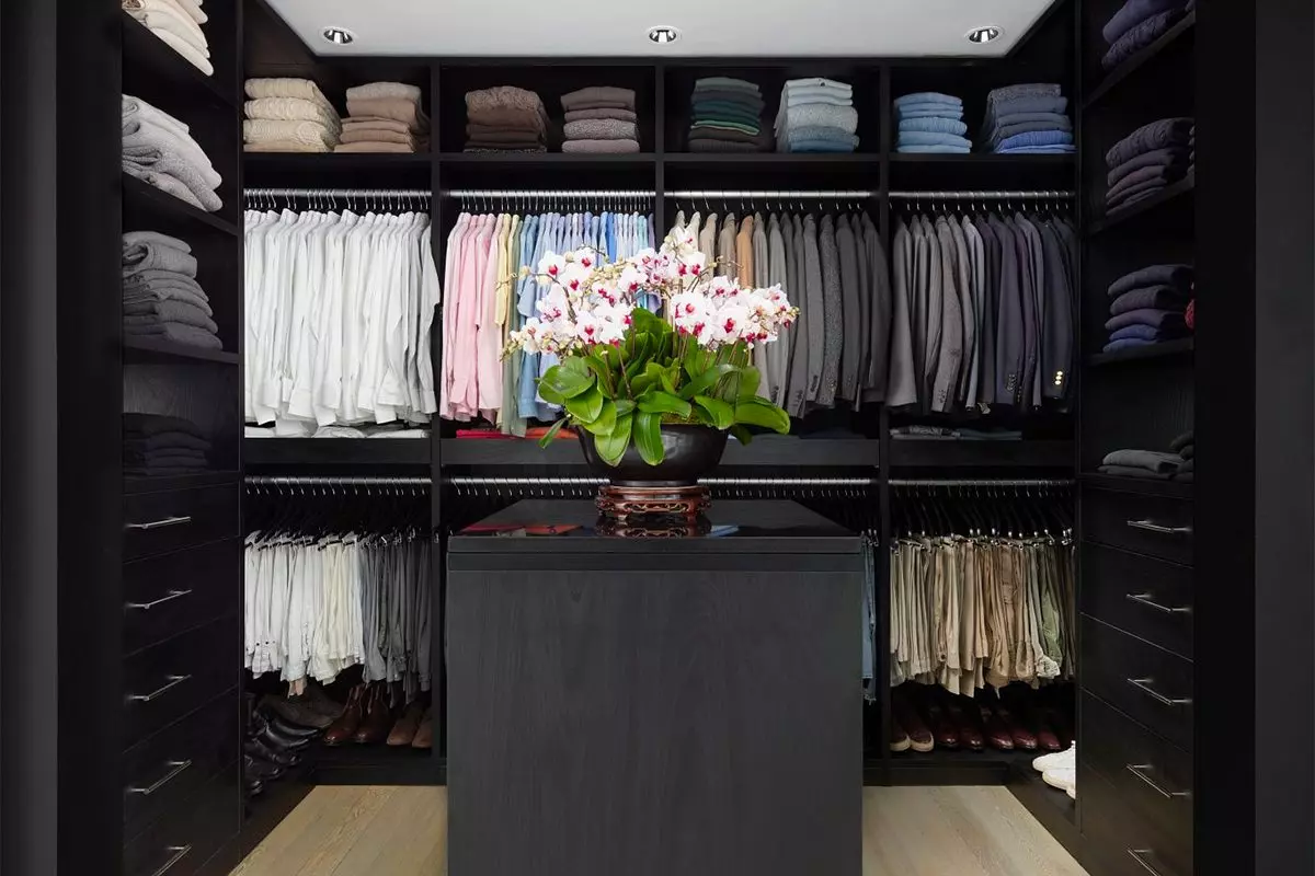 Dark wood finish walk-in closet with open shelves, clothes hanging poles and center island created by California Closets