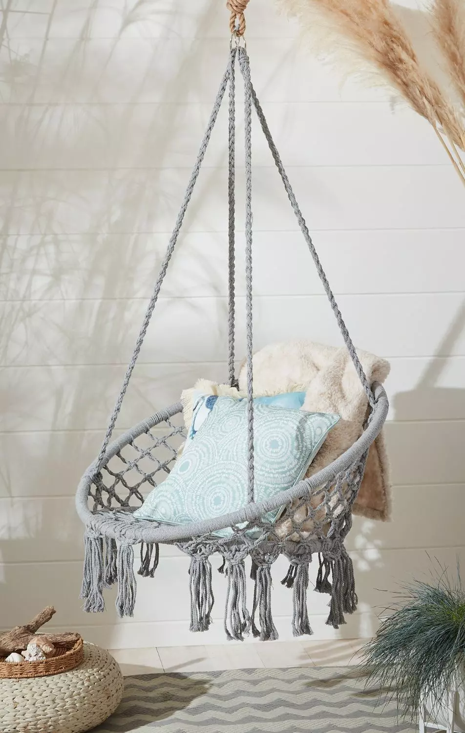 Rope hanging chair in the garden with sheepskin rug and blue cushion