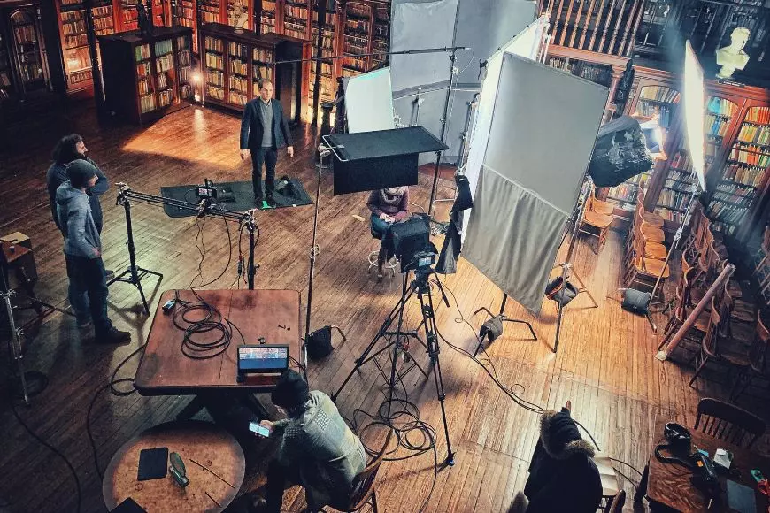 A group of people filming in a library.