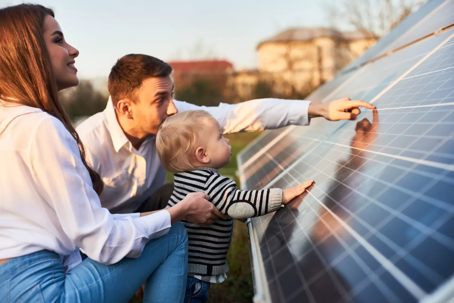 close-up shot of a young modern family with a little son getting acquainted with solar panel on a sunny day