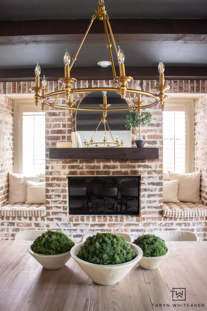 Tour this Modern Transitional Dining Room that features soft neutral textures and gold accents, combining cozy and elegant design. Lime wash walls and dark ceiling with beams.