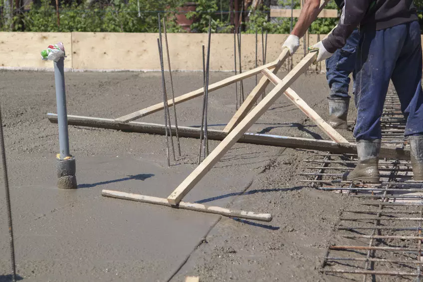 Concrete workers floating a wet, just-poured concrete slab to level it out and make it smooth