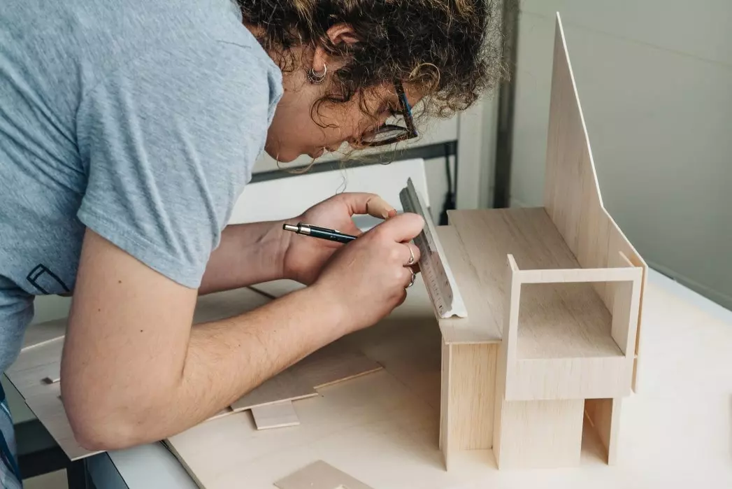 woman studying a model of a house being built