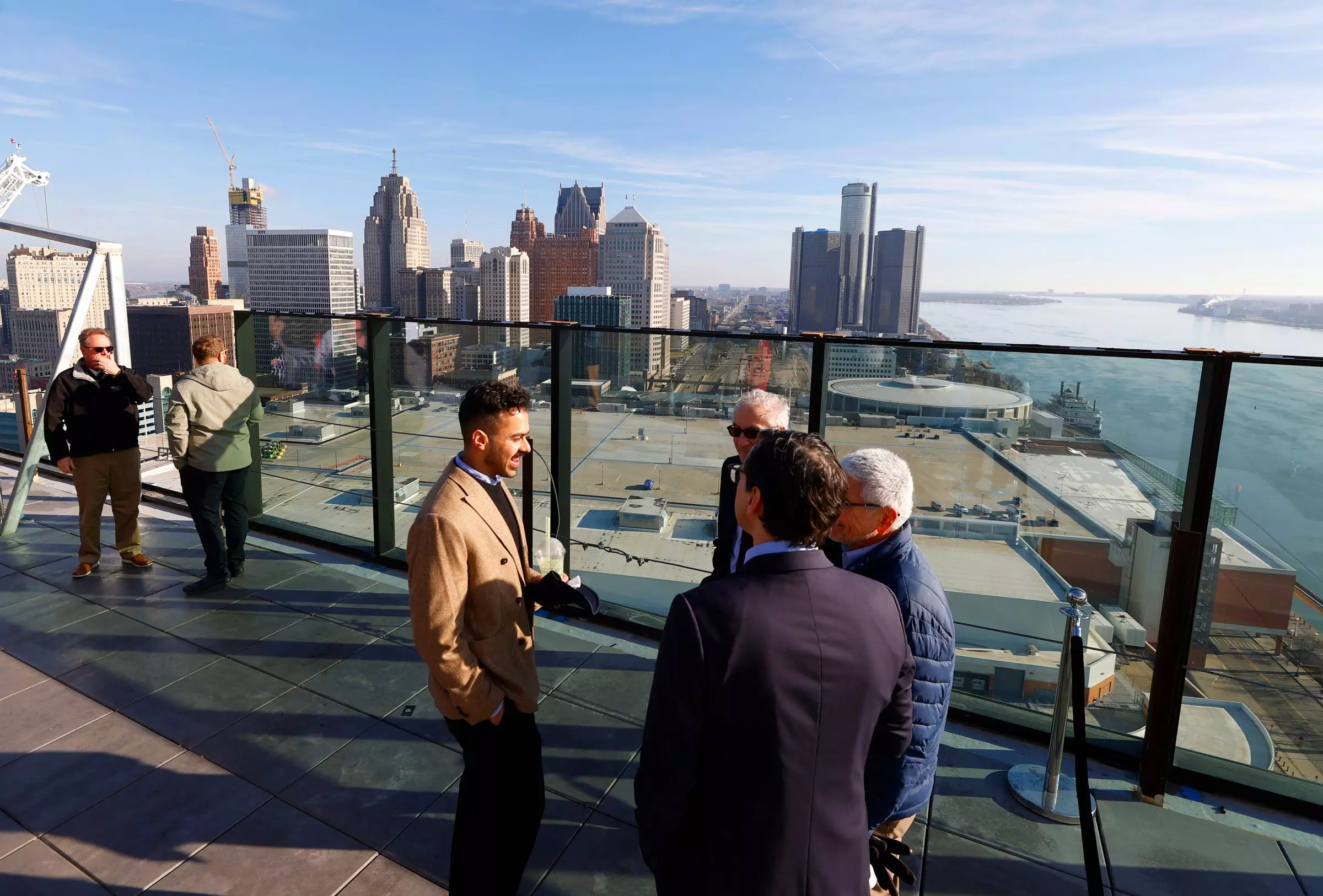 People talk on the 25th-floor observation area with the Detroit skyline in the background