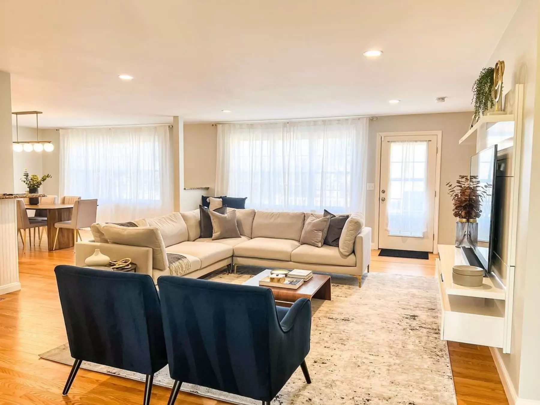 An L-shape sectional sofa and two armchairs atop a large rug in the living room.