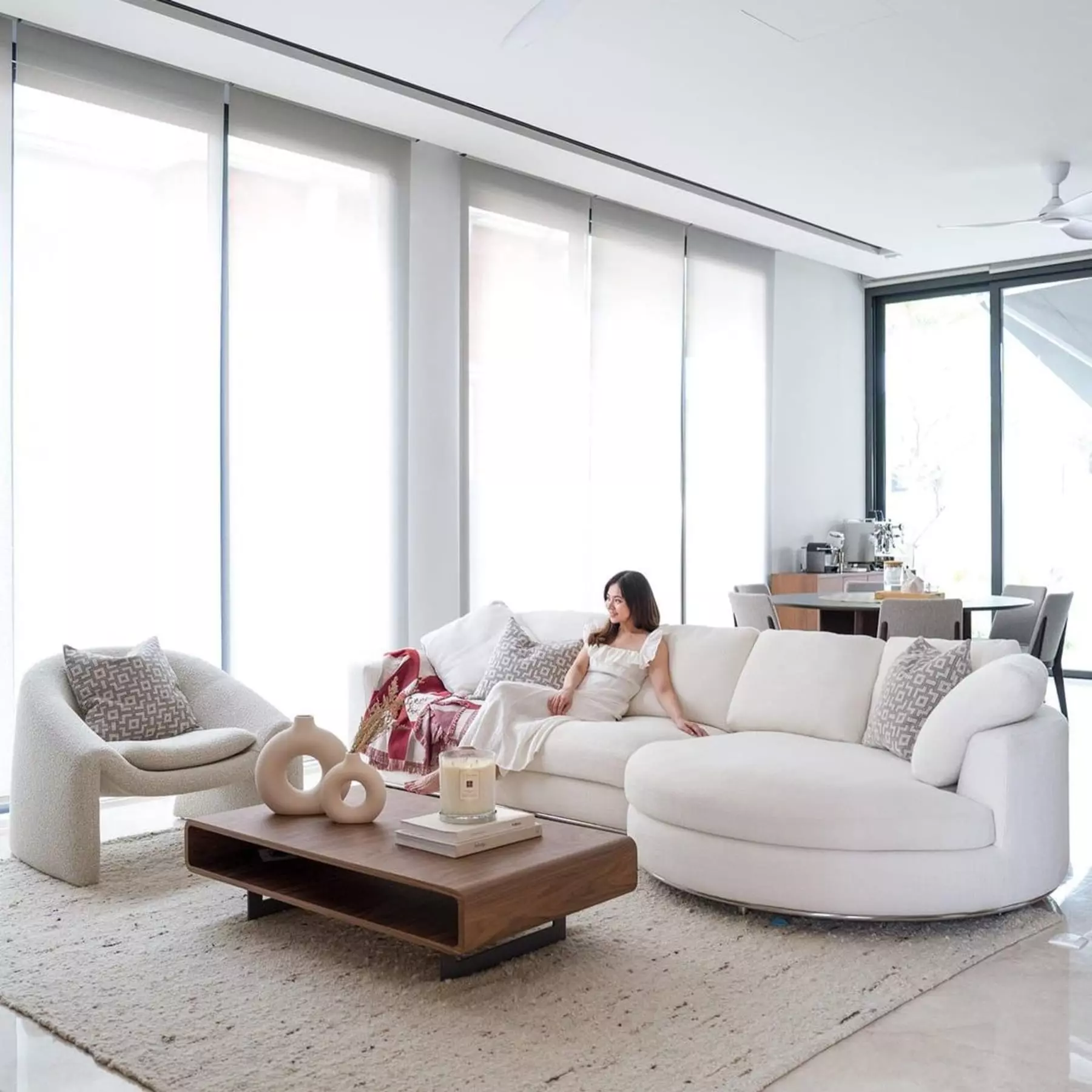 A person sitting on a round chaise sofa in the living room.