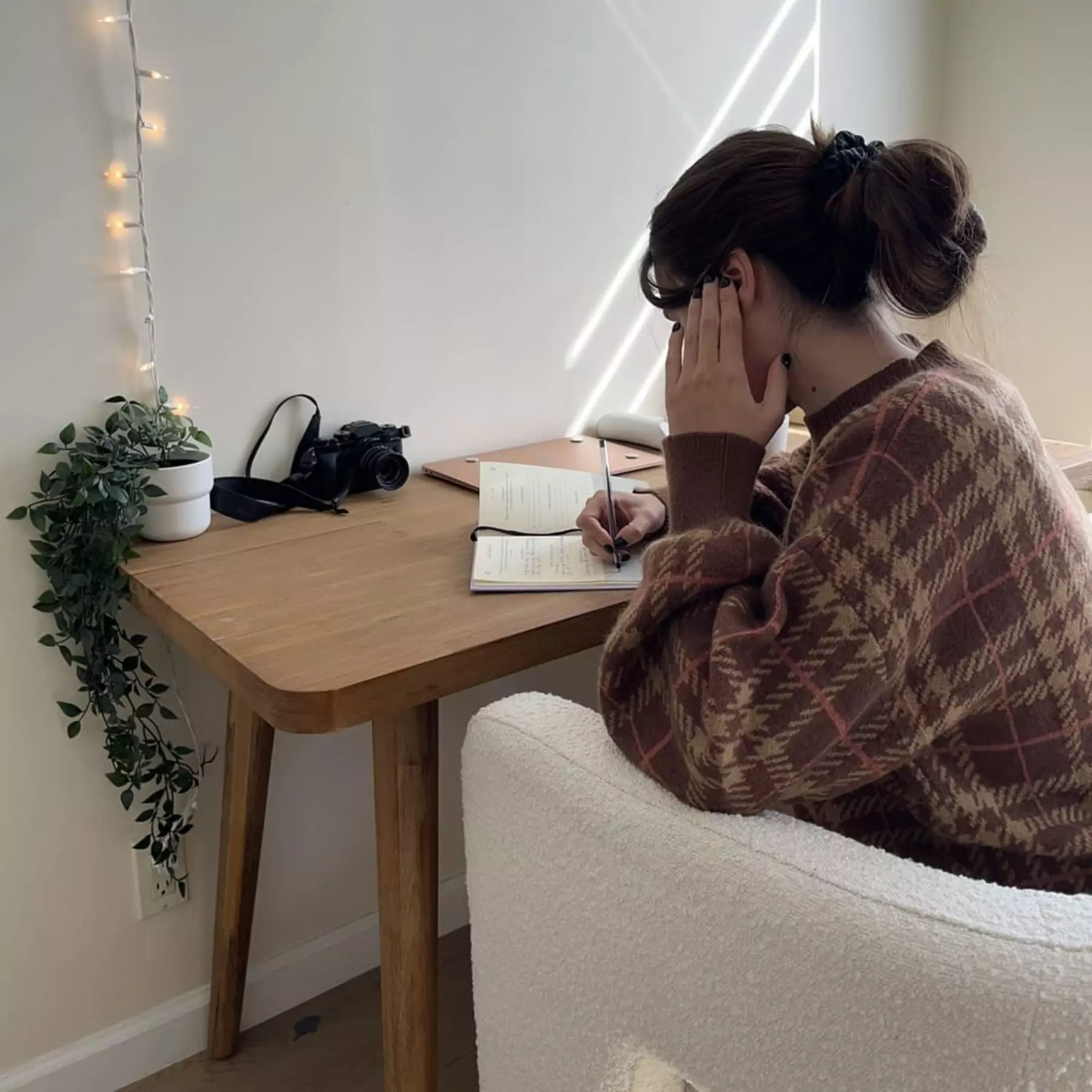 A person sitting on an armchair writing at their wooden desk.