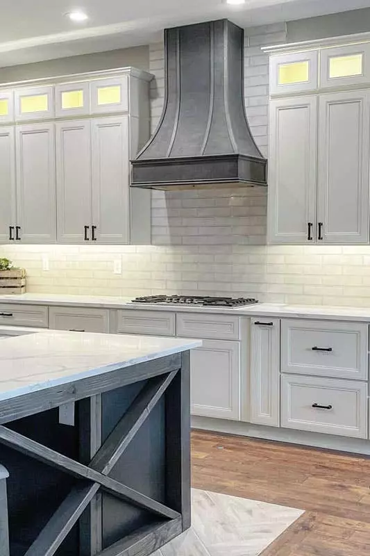 two toned kitchen feature linen and navy blue cabinets with ceiling lights and stainless steel hardware