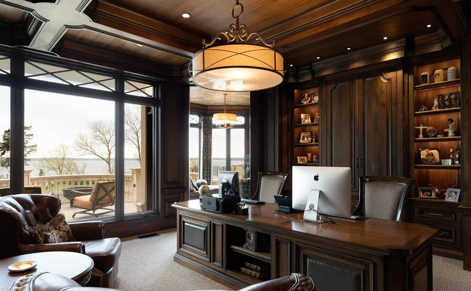 All dark wood office with wood wall paneling and wood ceiling. Matching wood desk. Tan carpeting. Large windows let in tons of natural light.