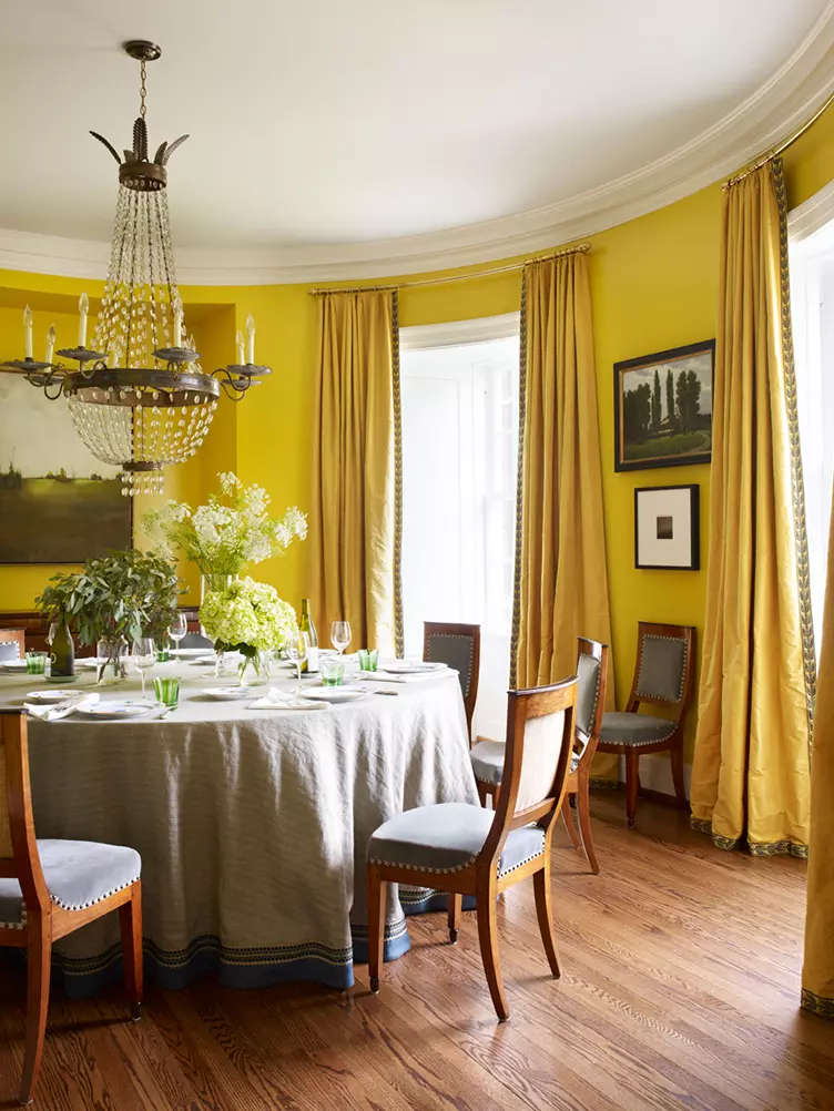 Traditional yellow dining room with traditional wood and upholstered dining chairs and crystal candelabra