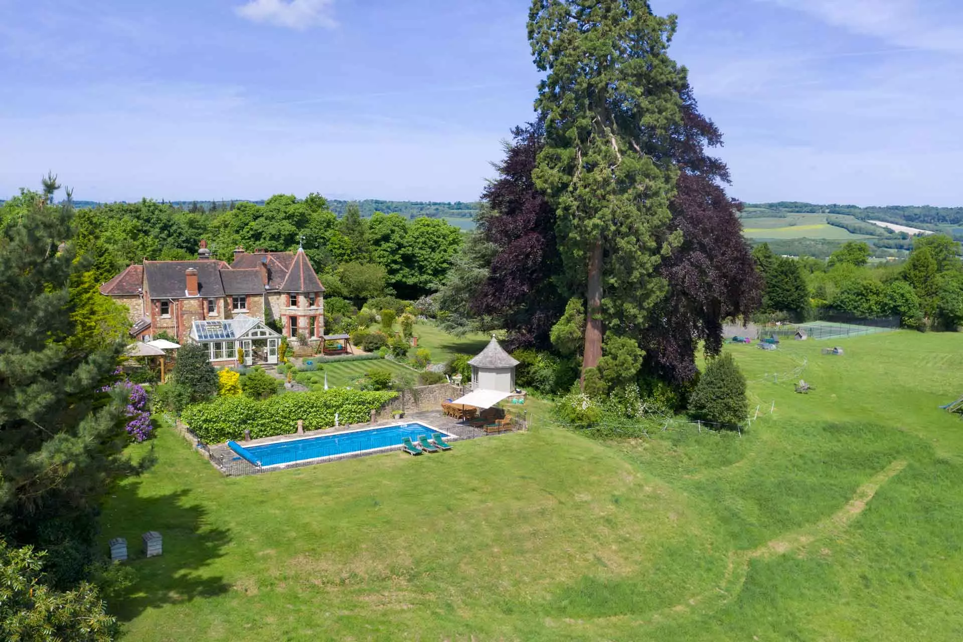 Aerial view of country manor with outhouses and grounds.