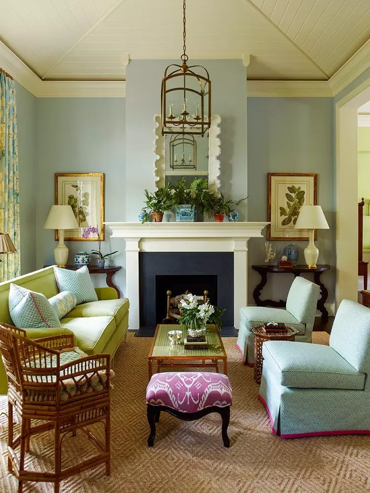 Beige slipper chair in traditional living room with large bookcase and dark walls.