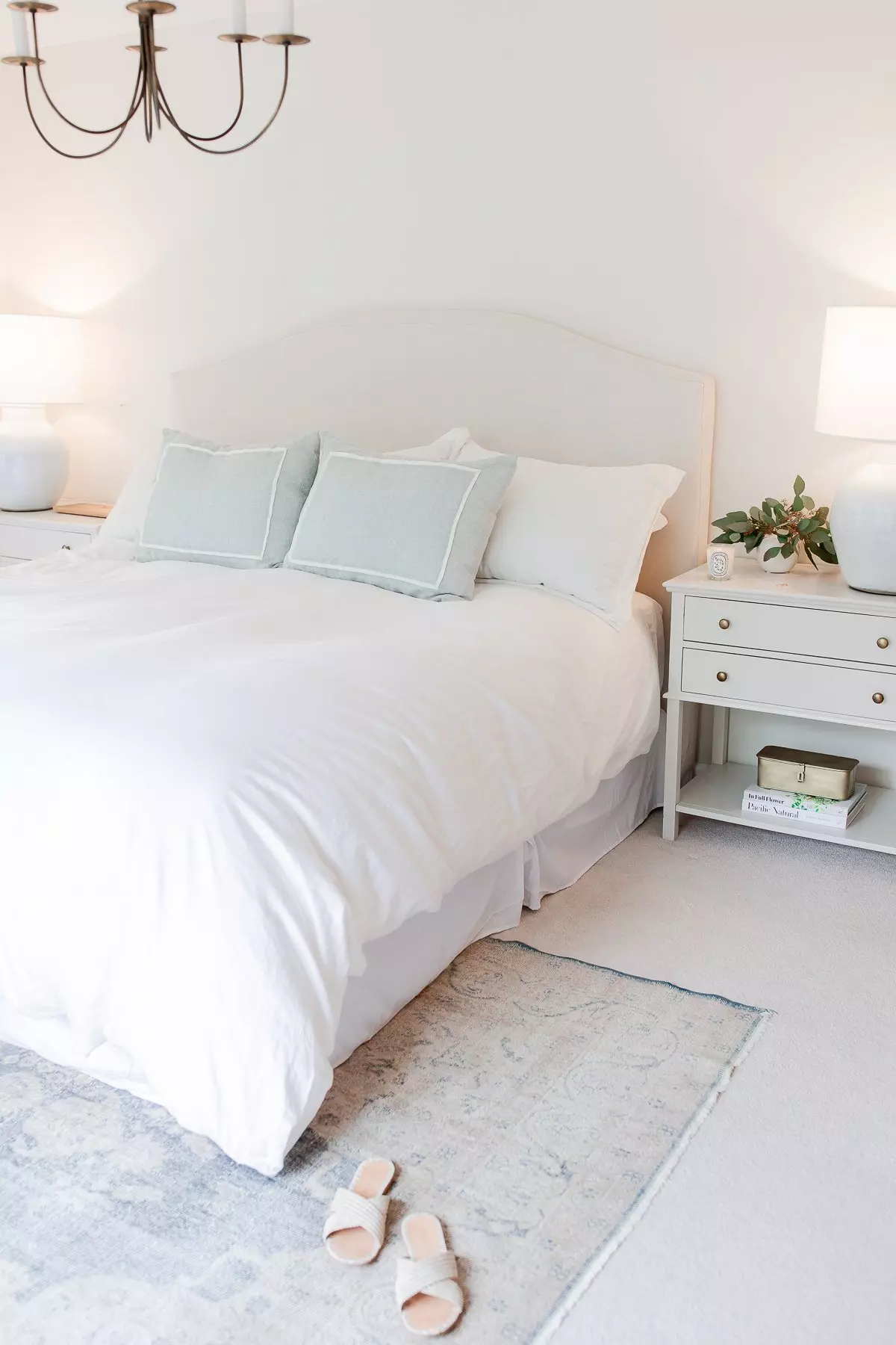 A bed with white sheets and pillows in a bedroom.