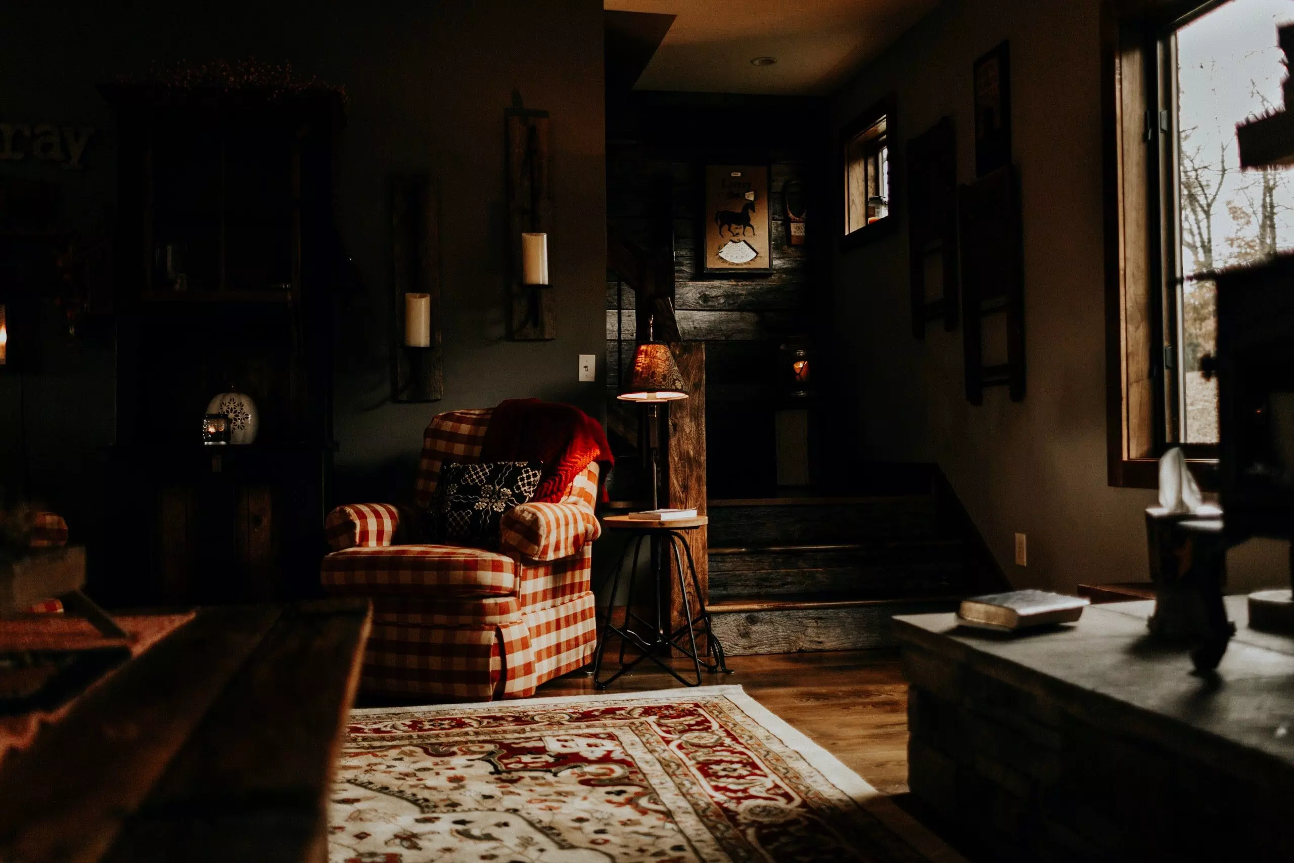 A low-key modern gothic living room with dark walls, dramatic light and shadows, and different textures.