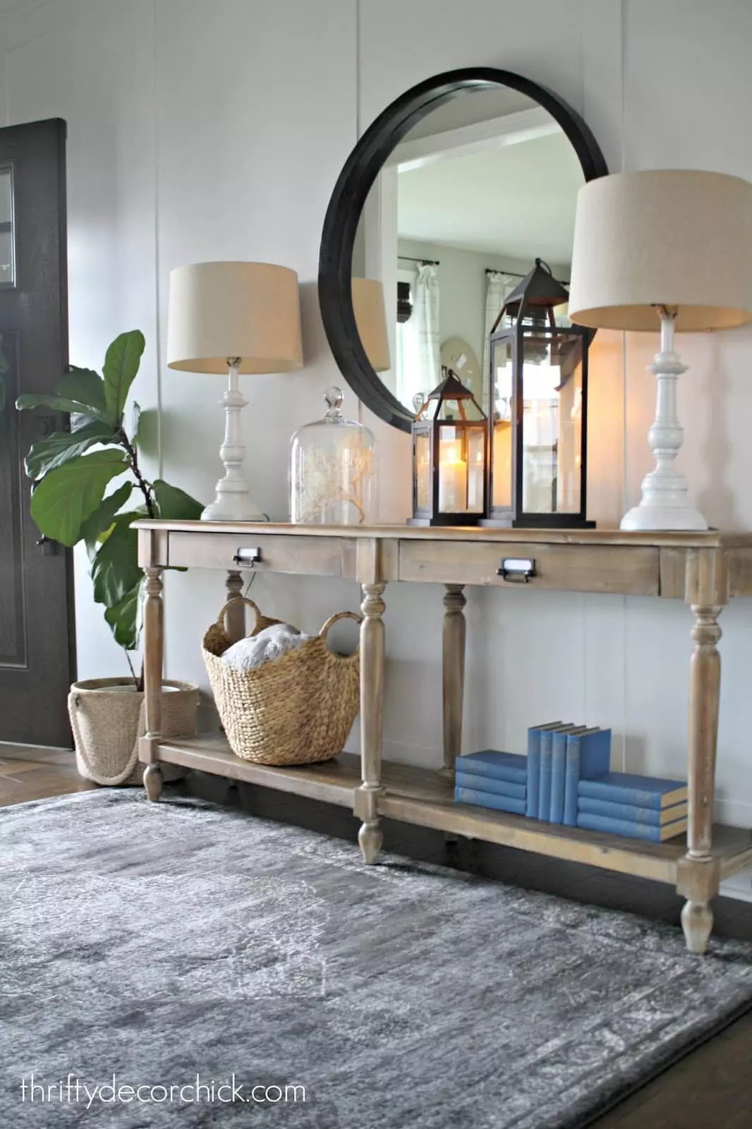 Raw wood entryway console table with large black mirror. The board and batten wall behind it is painted in Agreeable Gray