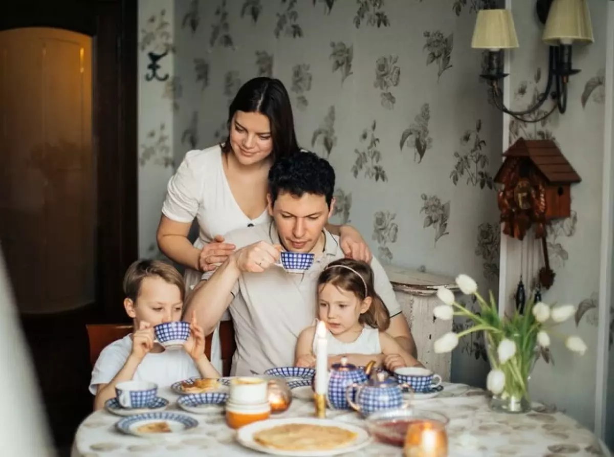 Family of four drinking tea at family kitchen table.